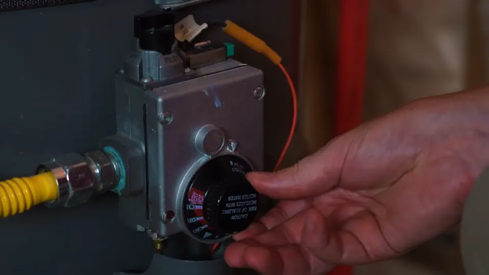 Hand adjusting the control on a gas water heater