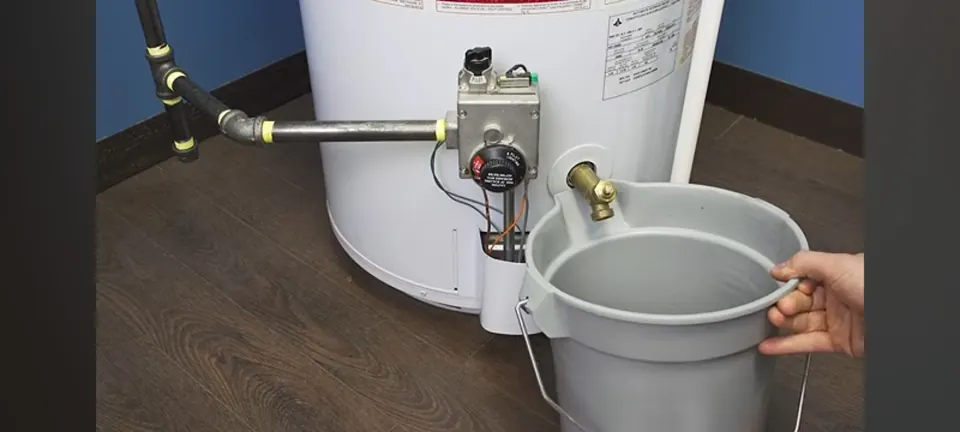 Bucket positioned beside a water heater drain valve